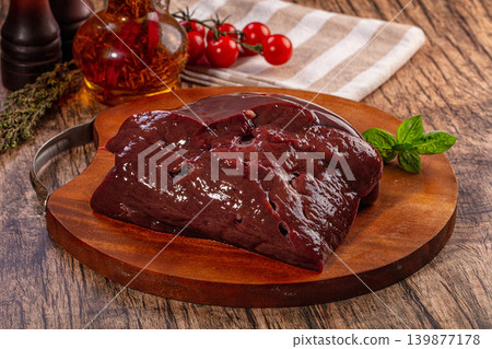 Fresh raw liver on rustic wooden cutting board with ingredients for cooking Fresh raw liver on rustic wooden cutting board with ingredients for cooking 139877178