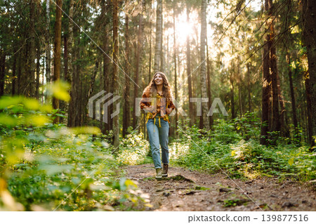 Stylish woman enjoying autumn weather in the park. Autumn mood. Hiking. 139877516