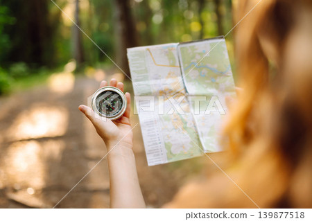 Traveler young woman searching direction with compass on background of map in the forest. Adventure Traveler young woman searching direction with compass on background of map in the forest. Adventure 139877518