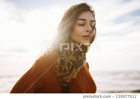 Woman enjoying breezy day near vibrant red lighthouse at sunset. Travel, weekend, lifestyle concept. Woman enjoying breezy day near vibrant red lighthouse at sunset. Travel, weekend, lifestyle concept. 139877812