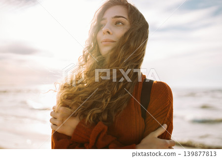 Woman enjoying breezy day near vibrant red lighthouse at sunset. Travel, weekend, lifestyle concept. Woman enjoying breezy day near vibrant red lighthouse at sunset. Travel, weekend, lifestyle concept. 139877813