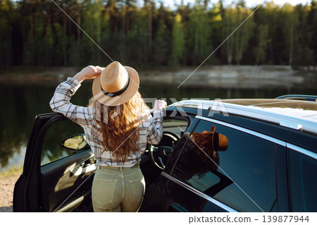 Joyful traveler embraces nature at sunset by lakeside with open car door, freedom, adventure. Joyful traveler embraces nature at sunset by lakeside with open car door, freedom, adventure. 139877944
