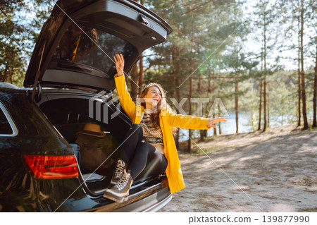 Young woman enjoying nature sitting in open trunk. Journey by car. Lifestyle, travel, nature concept Young woman enjoying nature sitting in open trunk. Journey by car. Lifestyle, travel, nature concept 139877990