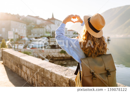 Woman tourist holding hands in shape of heart looking at panoramic landscape of city. Lifestyle. 139878122