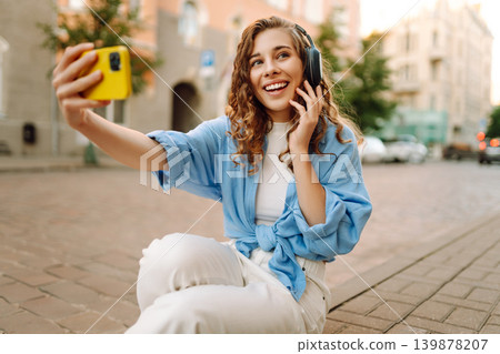 Happy young woman taking a selfie with headphones on a sunny day in a city street. Town lifestyles 139878207