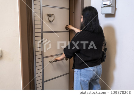 Female Securing House Door with Key. Female Securing House Door with Key. 139878268