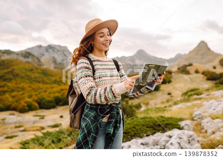 Young woman hiking in autumn landscape with a map. Travel, nature concept. Active lifestyle. Young woman hiking in autumn landscape with a map. Travel, nature concept. Active lifestyle. 139878352