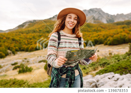 Young woman hiking in autumn landscape with a map. Travel, nature concept. Active lifestyle. 139878353
