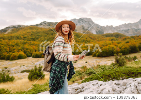 Young woman hiking in autumn landscape with a map. Travel, nature concept. Active lifestyle. Young woman hiking in autumn landscape with a map. Travel, nature concept. Active lifestyle. 139878365
