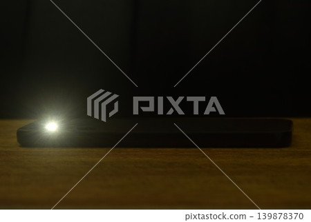 flashlight of mobile phone on table in dark night 139878370