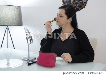 Woman Applying Makeup in Front of Mirror. Woman Applying Makeup in Front of Mirror. 139878376