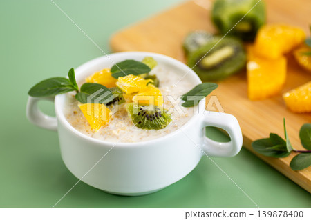 Creamy oatmeal with fresh fruit on green minimal background Creamy oatmeal with fresh fruit on green minimal background 139878400