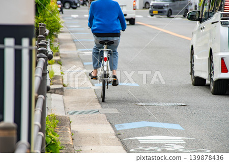 A cyclist riding on a bicycle navigation lane and a car passing by. A cyclist riding on a bicycle navigation lane and a car passing by. 139878436
