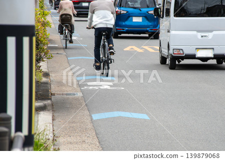 A cyclist riding on a bicycle navigation lane and a car passing by. A cyclist riding on a bicycle navigation lane and a car passing by. 139879068