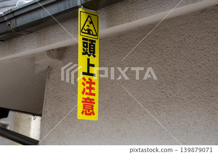 Warning tag for "Caution: Look out over your head under the eaves" 139879071