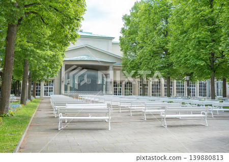 Well-maintained park zone with seating places and classical architecture in the background. Concept of urban landscaping, tourism, and outdoor recreation. 139880813