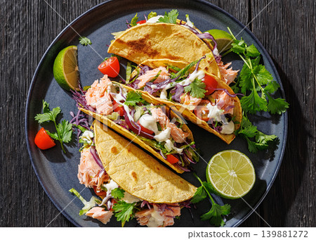 salmon tacos drizzled with sauce on a plate salmon tacos drizzled with sauce on a plate 139881272
