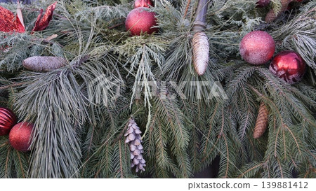 Close-up of a Christmas composition made of natural pine and spruce branches, cones, and red Christmas tree balls. Close-up of a Christmas composition made of natural pine and spruce branches, cones, and red Christmas tree balls. 139881412