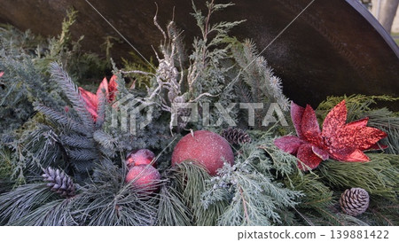 Close-up of a Christmas composition made of natural pine and spruce branches, cones, red Christmas tree balls and flowers. Close-up of a Christmas composition made of natural pine and spruce branches, cones, red Christmas tree balls and flowers. 139881422