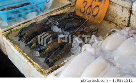 Seafood market counter displaying fresh shrimp and squid in trays with price tags at an outdoor street market in Thailand. Fresh catch concept 139881511