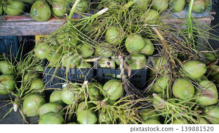 Large pile of fresh green coconuts displayed on a market counter at an Asian outdoor market stall. Tropical produce concept Large pile of fresh green coconuts displayed on a market counter at an Asian outdoor market stall. Tropical produce concept 139881520