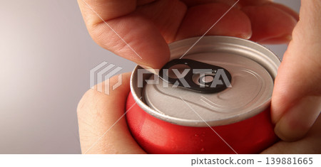 Cola or soda can opening. Close up of hand open aluminum beverage can with pull tab. Refreshing Cola or soda carbonated soft drink container with metal texture condensation droplets and easy open lid 139881665