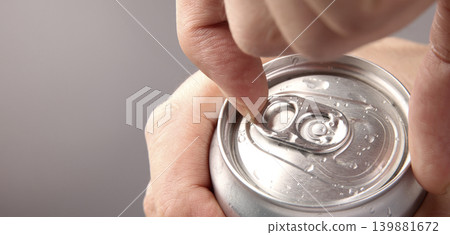 Cola or soda can opening. Close up of hand open aluminum beverage can with pull tab. Refreshing Cola or soda carbonated soft drink container with metal texture condensation droplets and easy open lid 139881672