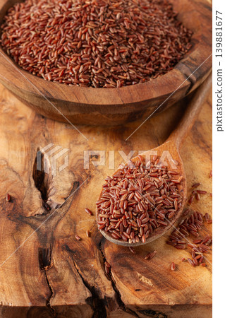 Natural red rice, in a wooden bowl and spoon on a wooden surface in rustic style, top view 139881677