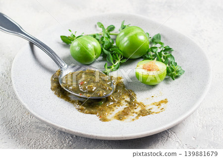 a spoon with tkemali sauce, on a plate, with cherry plum and mint, top view, no people, 139881679