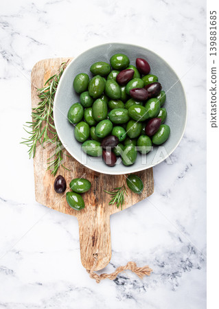 Chalkidiki olives, classic Greek green olives, in a bowl on a cutting board, top view, without people, Chalkidiki olives, classic Greek green olives, in a bowl on a cutting board, top view, without people, 139881685