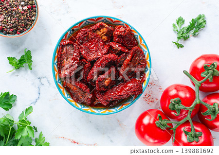Dried tomatoes, in a bowl with fresh herbs and spices, on a white marble surface, no people Dried tomatoes, in a bowl with fresh herbs and spices, on a white marble surface, no people 139881692