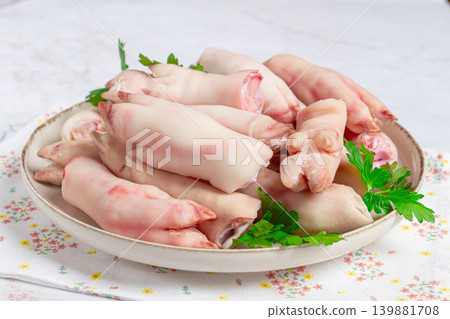 Pork trotters arranged on a plate with fresh parsley on a white background Pork trotters arranged on a plate with fresh parsley on a white background 139881708
