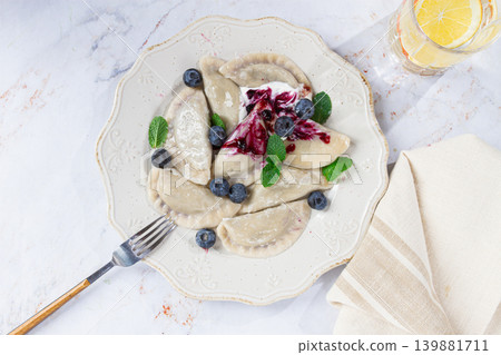 Delicious homemade dumplings served with berry sauce and fresh blueberries on a white plate Delicious homemade dumplings served with berry sauce and fresh blueberries on a white plate 139881711