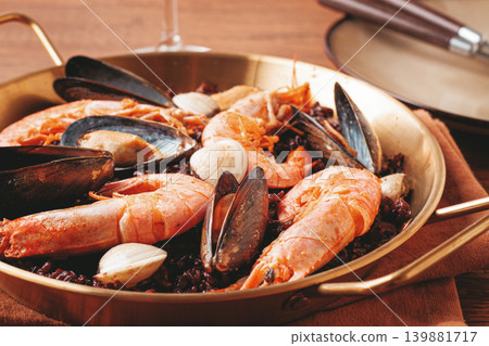 seafood and black rice paella, in a frying pan, homemade, on a wooden table, no people, seafood and black rice paella, in a frying pan, homemade, on a wooden table, no people, 139881717