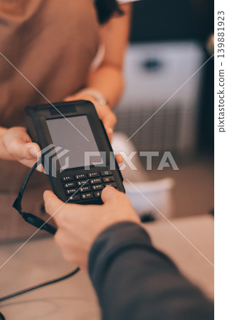 Asian senior female barista adult receiving mobile payment from customer using smartphone at cafe demonstrating modern cashless transaction in cozy local family coffee shop 139881923