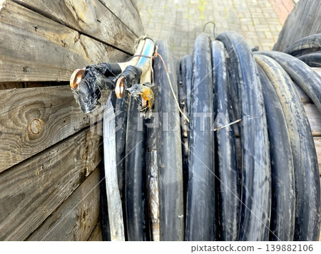 Electric Cable on a Reel Placed Near a Wooden Wall With Frayed Ends Visible Electric Cable on a Reel Placed Near a Wooden Wall With Frayed Ends Visible 139882106