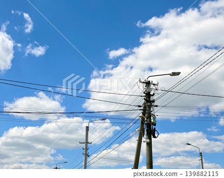 Electricity Poles Stand Against a Blue Sky With Clouds in the Background Electricity Poles Stand Against a Blue Sky With Clouds in the Background 139882115