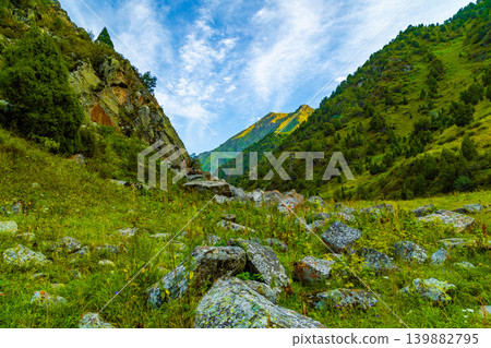 Scenic Mountain Valley with Sunlit Peaks and Blue Sky in Kyrgyzstan Scenic Mountain Valley with Sunlit Peaks and Blue Sky in Kyrgyzstan 139882795