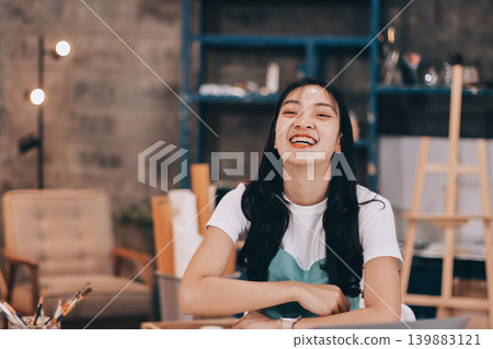 Female artist wears black hat posing near picture indoor the studio 139883121
