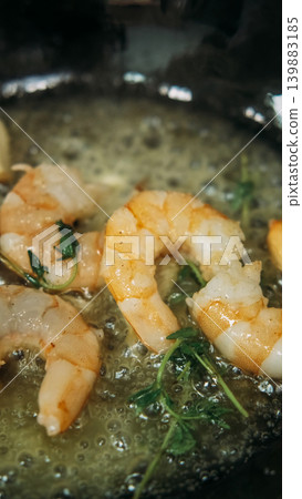 Cooking shrimp. Appetizer recipe. Prawn sizzling in black pan with bubbling butter fresh herbs. Delicious gourmet food preparation. Cooking shrimp. Appetizer recipe. Prawn sizzling in black pan with bubbling butter fresh herbs. Delicious gourmet food preparation. 139883185