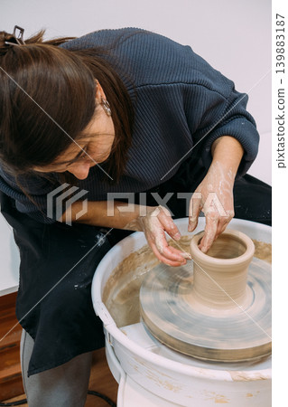 Clay modeling. Ceramic art. Professional female specialist working with raw using pottery electric wheel in artisan workplace. Clay modeling. Ceramic art. Professional female specialist working with raw using pottery electric wheel in artisan workplace. 139883187