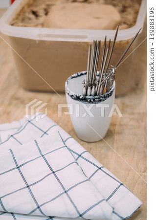 Clay tools. Pottery workspace. Professional ceramic sculpting instruments checkered cloth on wooden surface for creative handmade artisan craft. 139883196