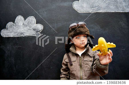 Kids, chalkboard and toy plane with boy in studio on black background for fantasy game. Education, imagine and class pilot in costume playing at school for growth, learning or child development 139883636