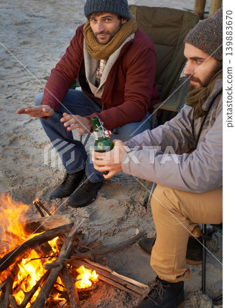 Men, sunset and campfire with portrait, smile and beer with travel adventure and journey outdoor. Friends, ocean and sea with bonding, winter and vacation by the beach together on holiday with fire Men, sunset and campfire with portrait, smile and beer with travel adventure and journey outdoor. Friends, ocean and sea with bonding, winter and vacation by the beach together on holiday with fire 139883670