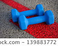 Blue dumbbells on red track surface outdoor fitness training equipment 139883772