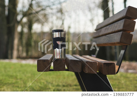 Thermos cup on wooden bench in park calm morning scene 139883777
