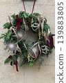 Luxury festive wreath with metallic ornaments hanging on stone exterior wall 139883805