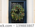 Decorated spruce wreath hanging on elegant black iron framed window 139883807