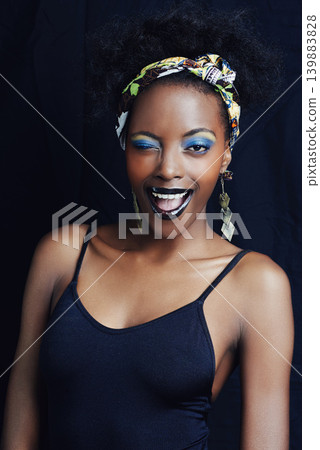 African woman, wink and studio for makeup, style and smile for eye shadow and glamour. Black female model, dark background and cosmetic, portrait and face for cultural, fashion and elegant earrings African woman, wink and studio for makeup, style and smile for eye shadow and glamour. Black female model, dark background and cosmetic, portrait and face for cultural, fashion and elegant earrings 139883828