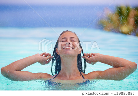 Face, smile and rain with woman in swimming pool for travel, holiday or vacation as tourist. Relax, water and wellness with happy young swimmer person outdoor at tropical resort for getaway trip Face, smile and rain with woman in swimming pool for travel, holiday or vacation as tourist. Relax, water and wellness with happy young swimmer person outdoor at tropical resort for getaway trip 139883885